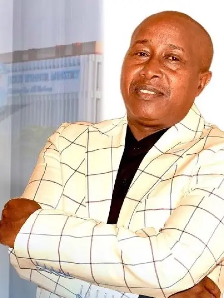 Apostle James Kiongo in a cream checked blazer, arms folded