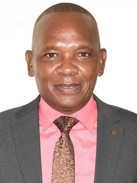 Rev. Kibiego in a charcoal suit, pink shirt and patterned tie